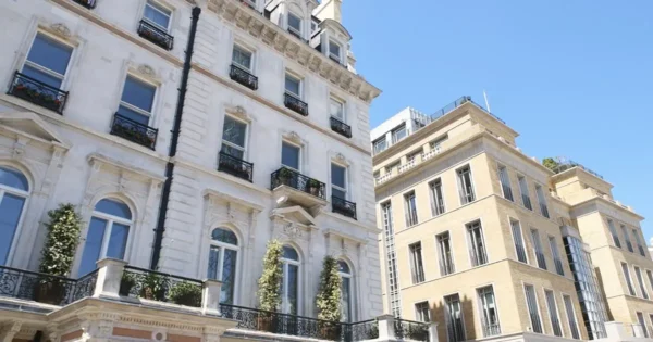 Exterior of elegant, multi-storey residential buildings with ornate balconies and large windows against a clear blue sky.